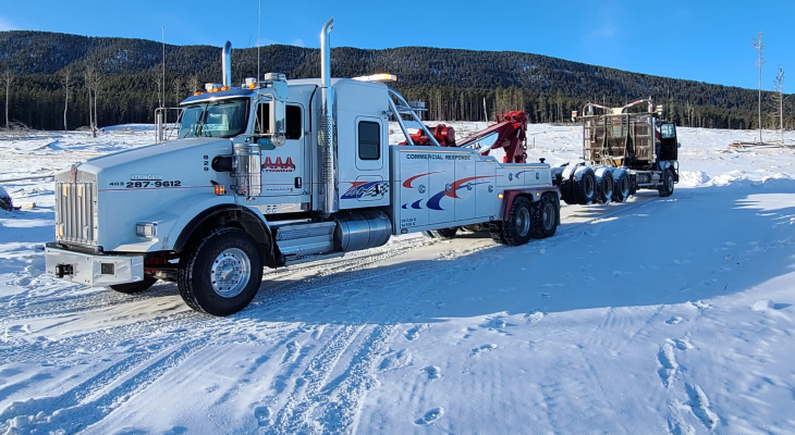 Heavy-duty wrecker tow truck stationed on a snowy road assisting with winter roadside assistance and battery boosting Calgary